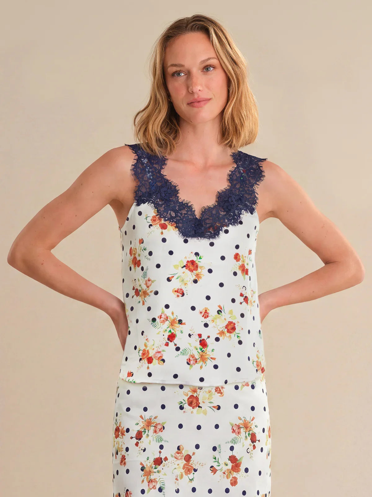 Woman wearing a sleeveless top with floral and polka dot patterns on a beige background