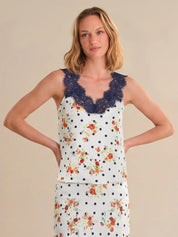 Woman wearing a sleeveless top with floral and polka dot patterns on a beige background