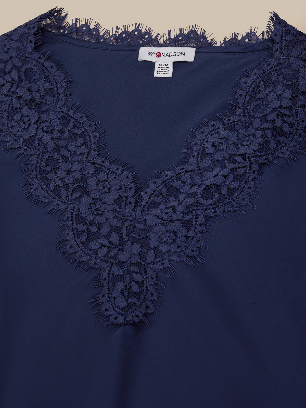 Navy blue top with lace detailing on a beige background