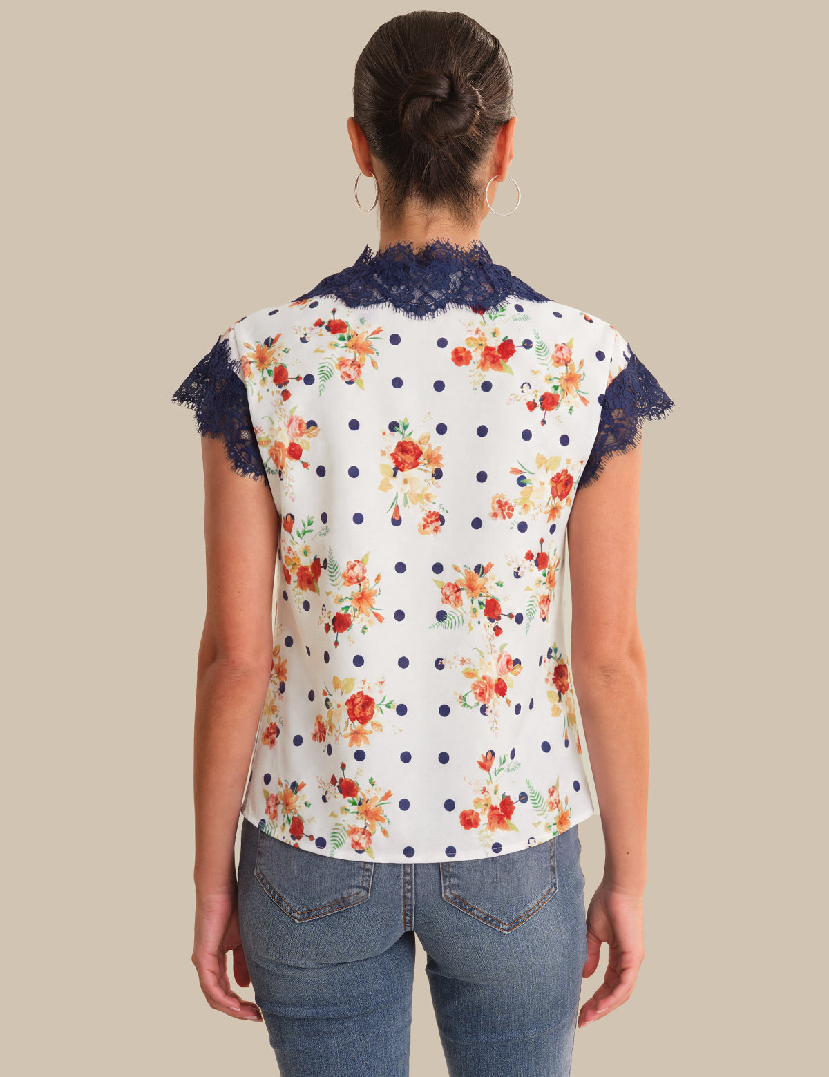 Woman wearing a floral blouse with lace trim on a beige background
