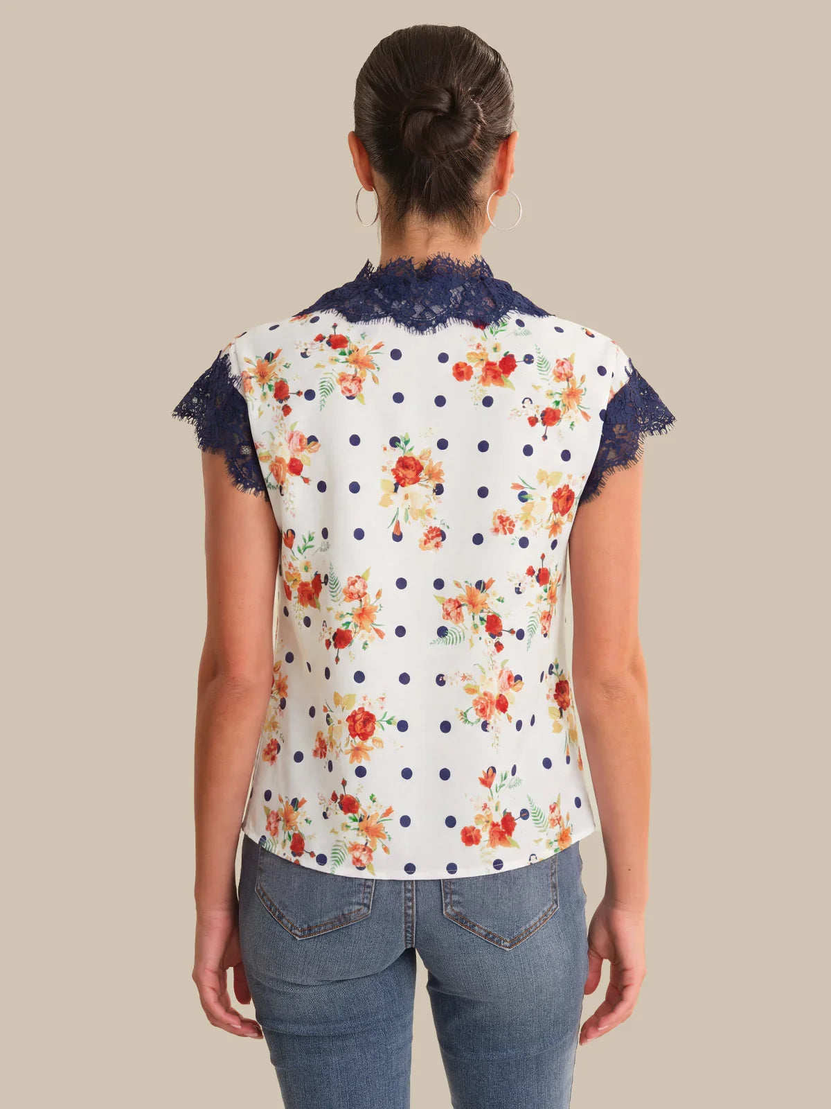 Woman wearing a floral blouse with lace trim on a beige background