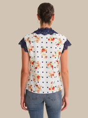 Woman wearing a floral blouse with lace trim on a beige background