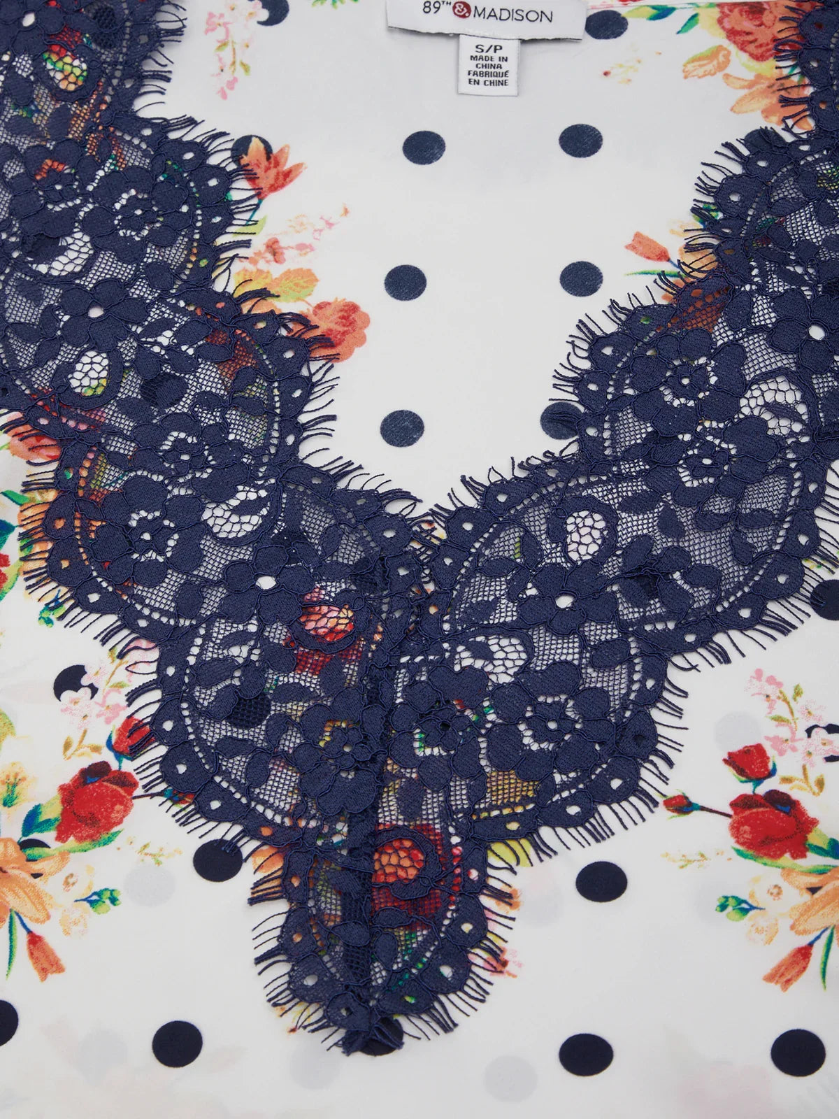 Navy lace collar on a white fabric with floral and polka dot patterns
