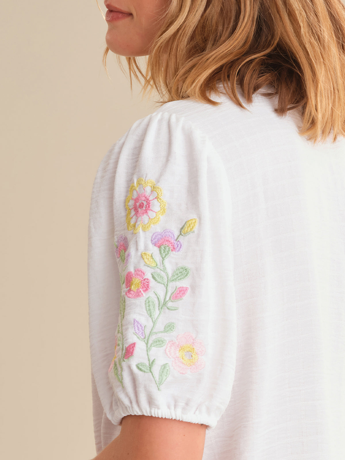 White blouse with floral embroidery on a beige background