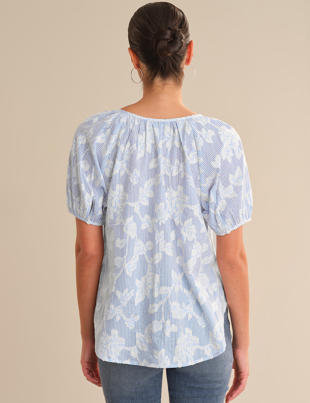 Person wearing a light blue floral blouse against a beige background