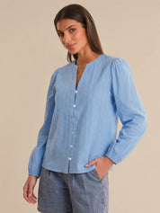 Woman wearing a light blue blouse with a beige background