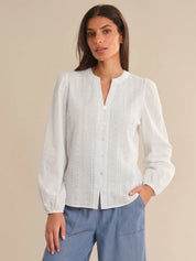 Woman wearing a white blouse with long sleeves against a beige background