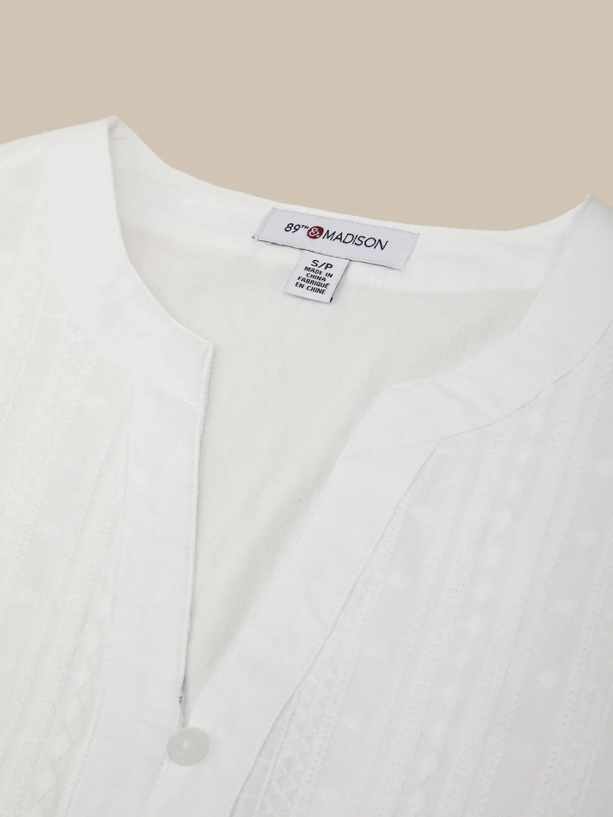 White blouse with a visible brand label on a beige background