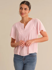 Woman wearing a pink blouse and blue jeans on a beige background