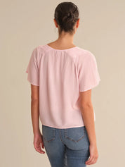 Person wearing a light pink blouse and blue jeans on a beige background