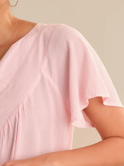 Close-up of a person wearing a light pink dress with a neutral background