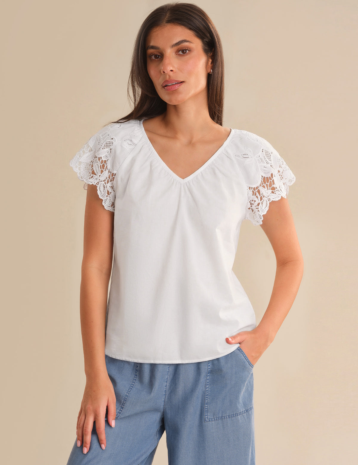 Woman wearing a white blouse with lace sleeves on a beige background