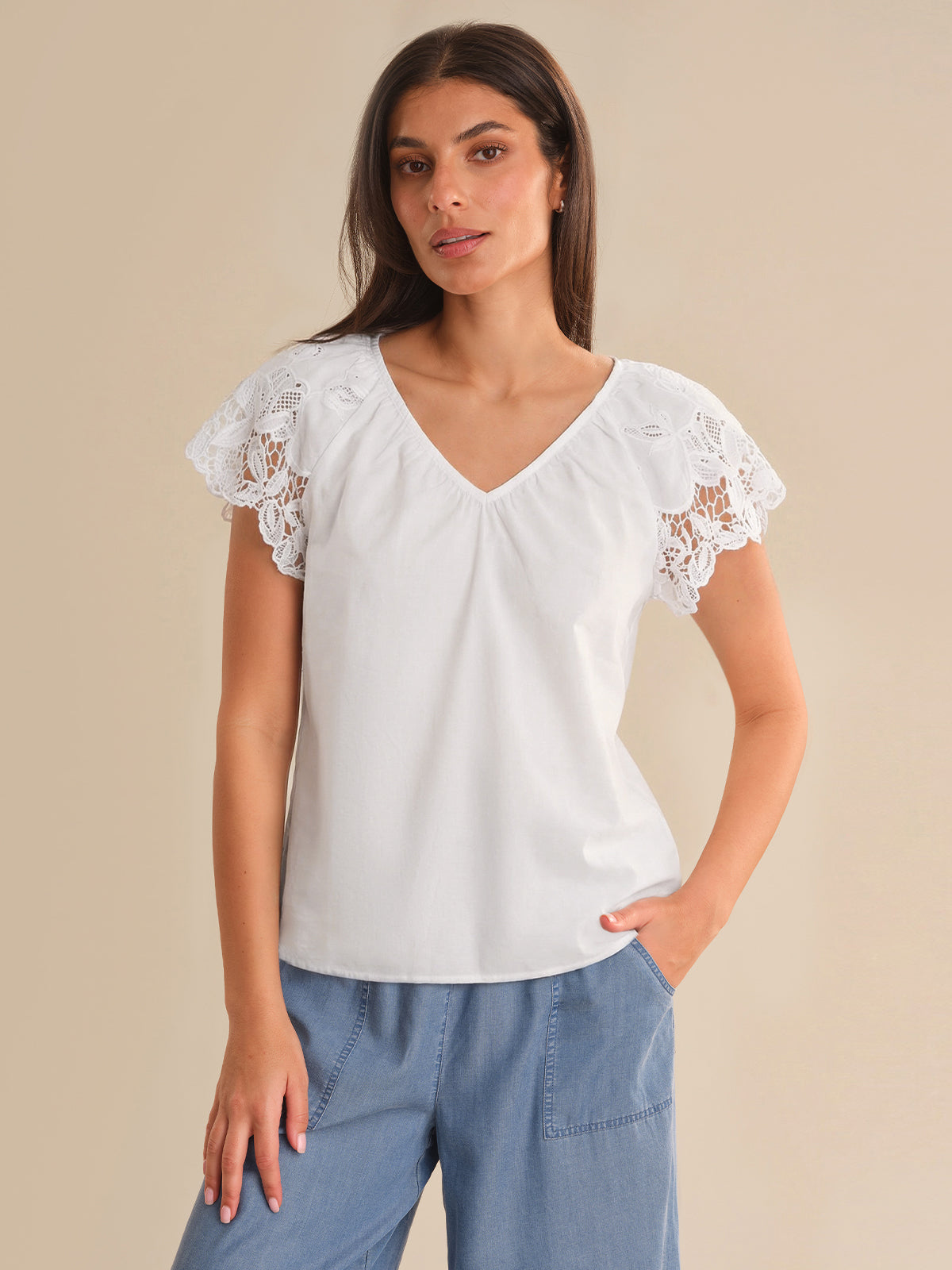 Woman wearing a white blouse with lace sleeves on a beige background
