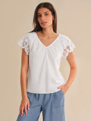 Woman wearing a white blouse with lace sleeves on a beige background