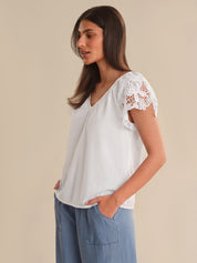 Woman wearing a white blouse with lace sleeves on a beige background