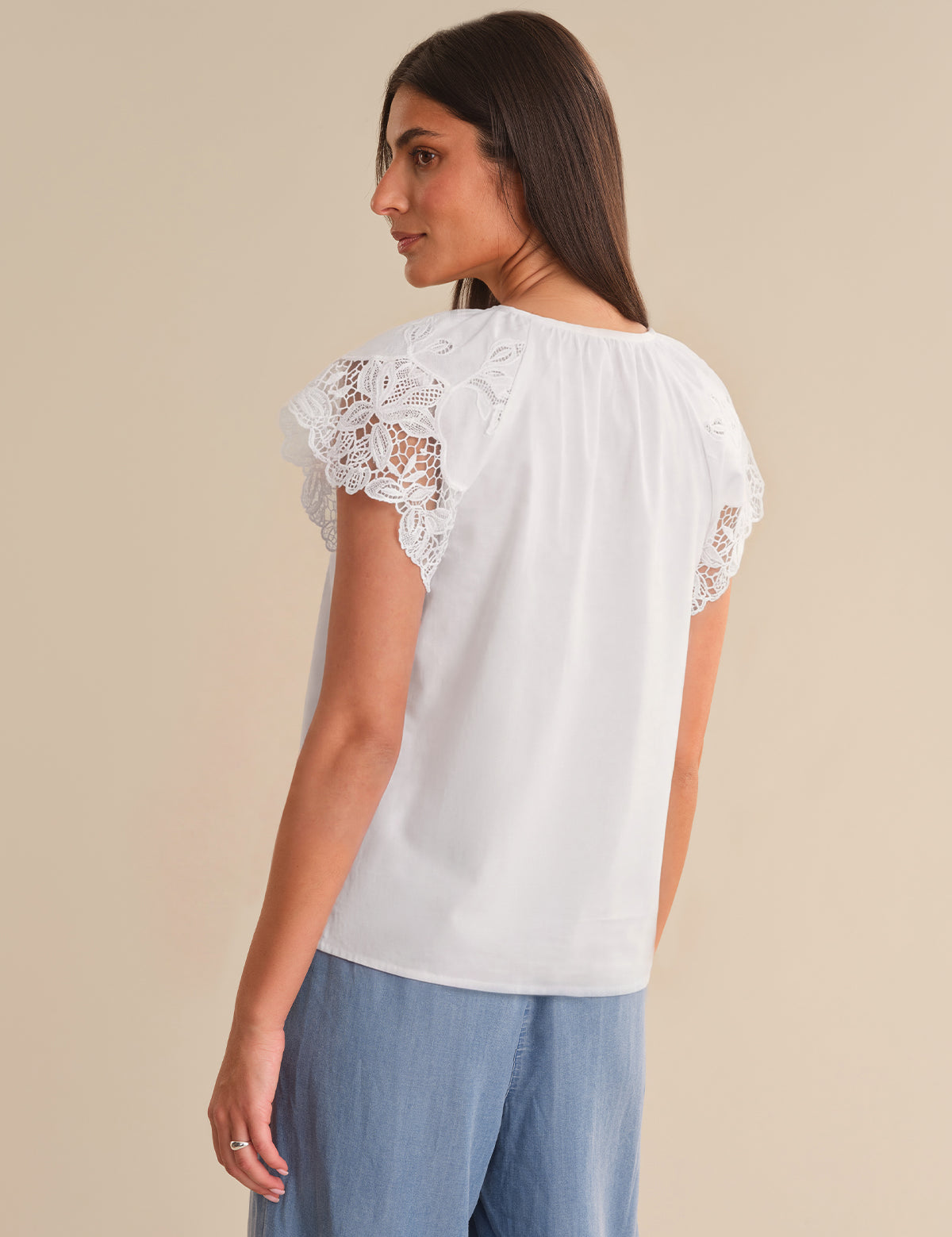 Woman wearing a white blouse with lace sleeves on a beige background