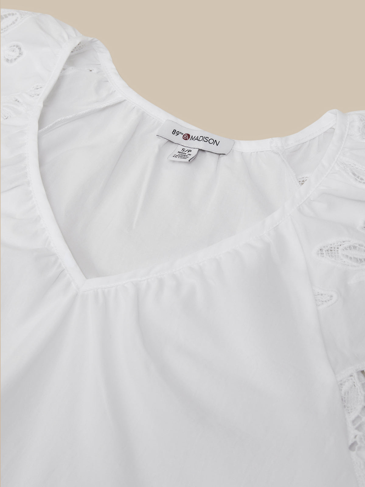 White blouse with ruffled details on a beige background