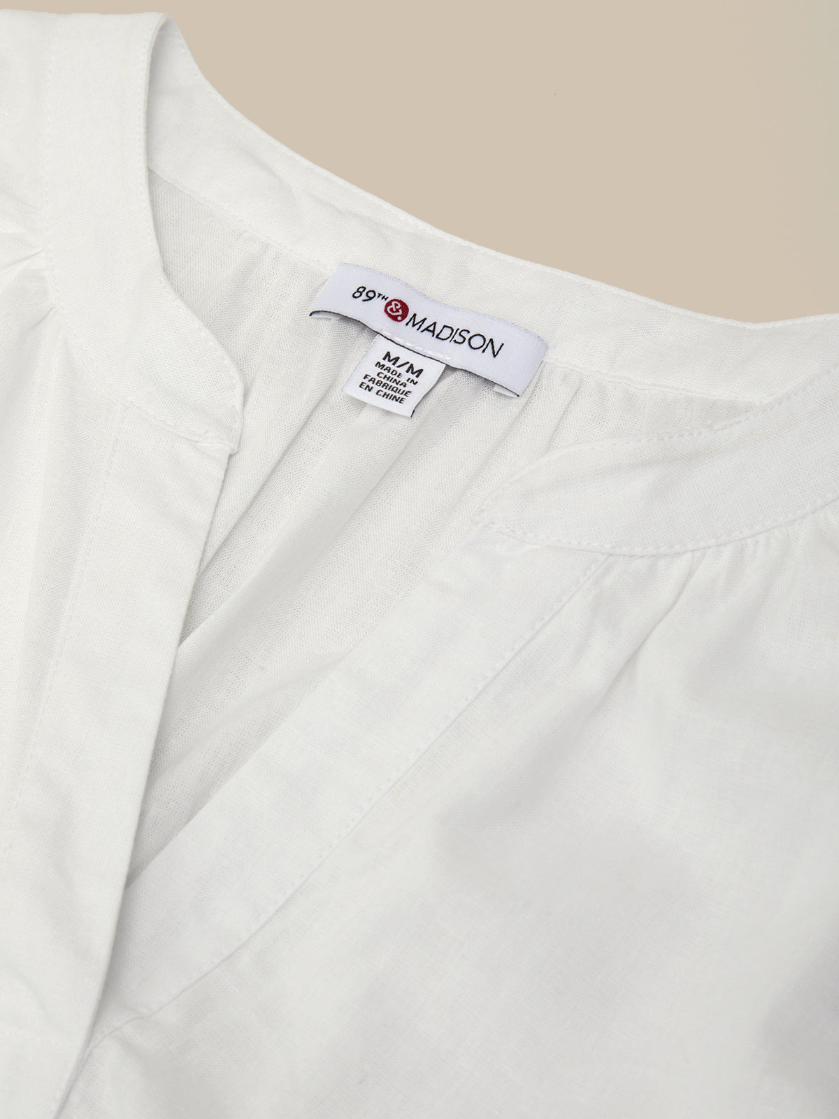 Close-up of a white garment with a visible label on a beige background