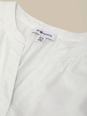 Close-up of a white garment with a visible label on a beige background