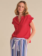 Woman wearing a red blouse and striped pants on a beige background