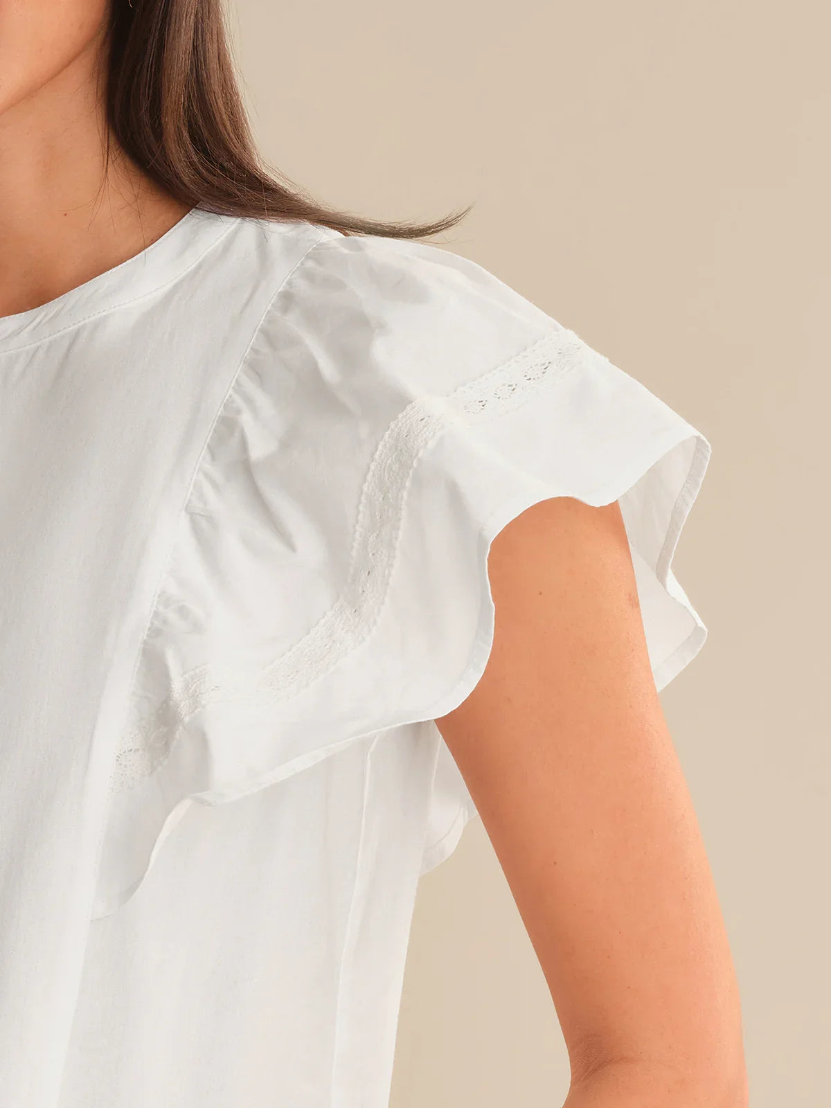 White blouse with short sleeves worn by a person on a beige background