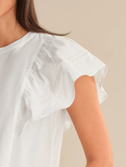 White blouse with short sleeves worn by a person on a beige background