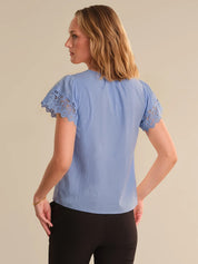 Woman wearing a light blue blouse with lace sleeves on a beige background