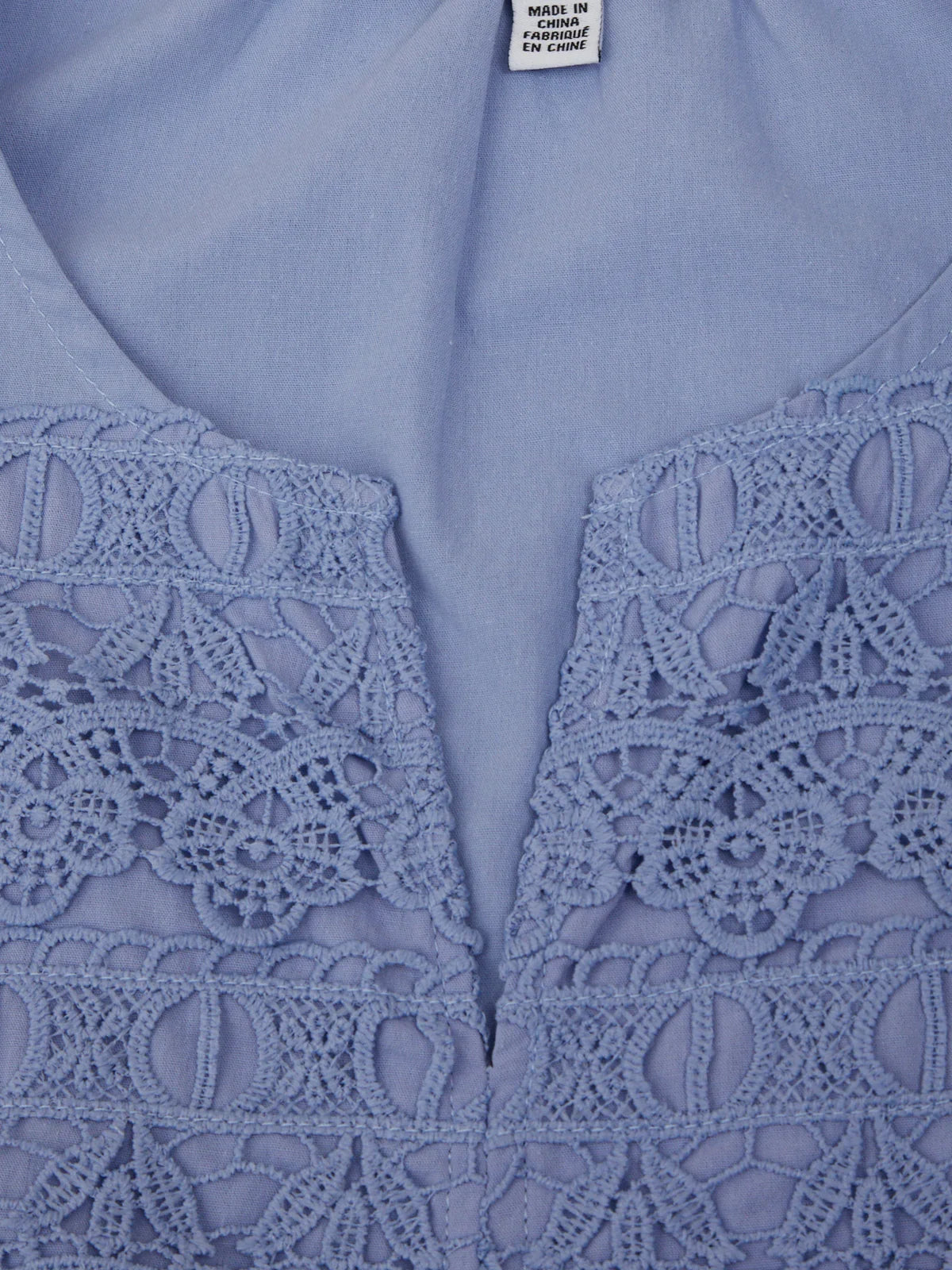 Close-up of a light blue blouse with lace detailing on the neckline.