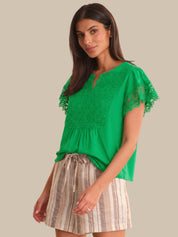 Woman wearing a green lace top and striped skirt on a beige background
