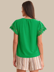 Woman wearing a green top with lace sleeves on a beige background