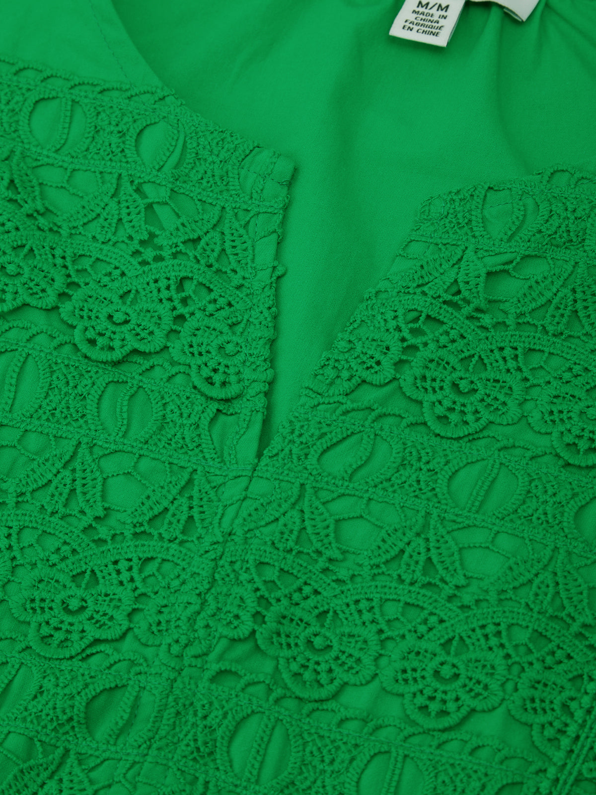 Green lace top with a tag on a green background