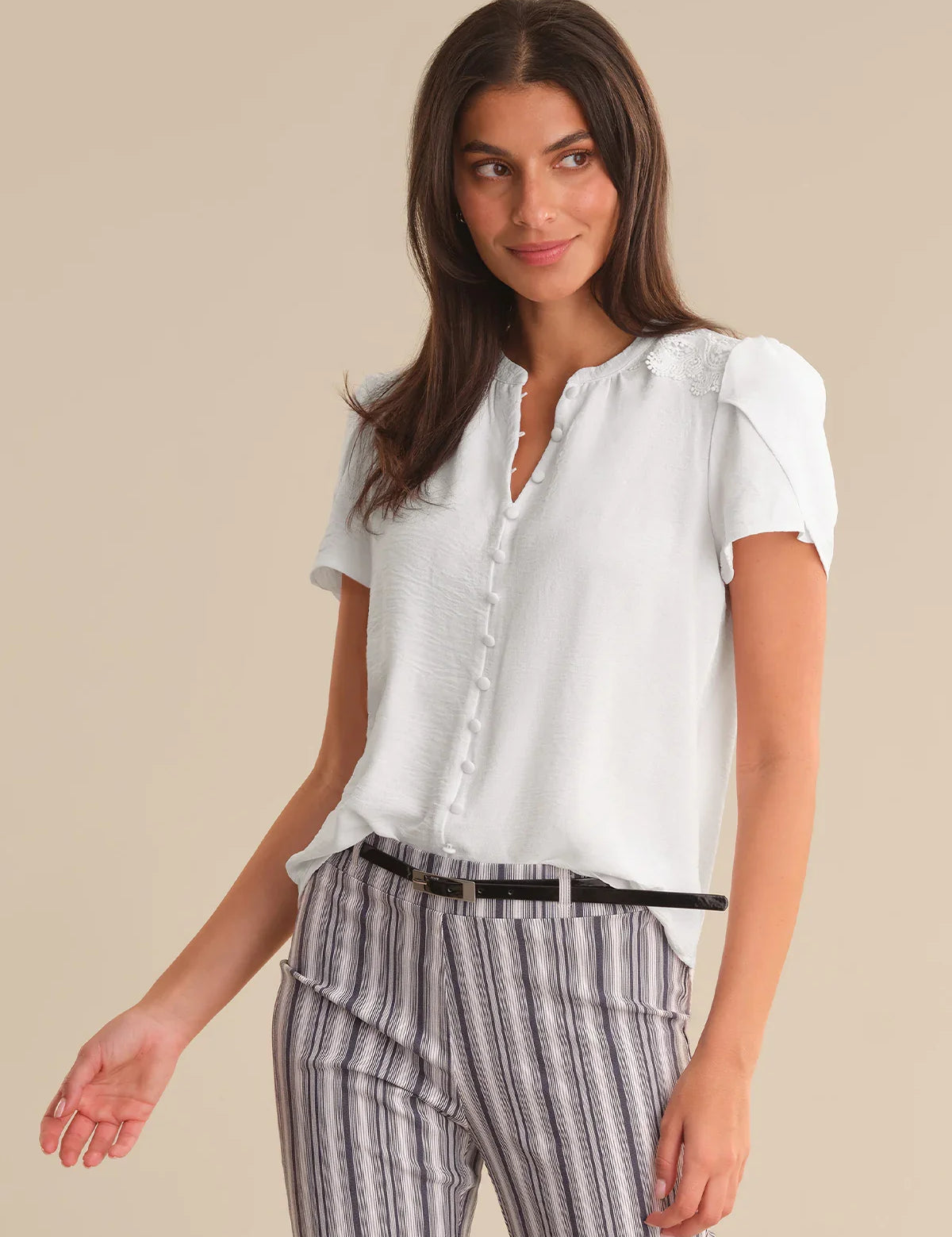Woman wearing a white blouse and striped pants on a beige background