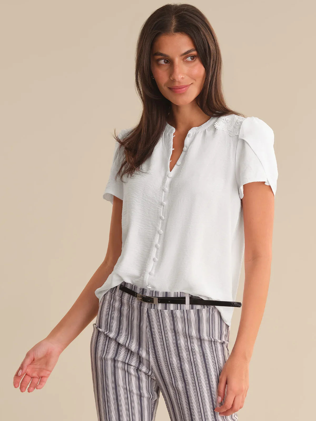 Woman wearing a white blouse and striped pants on a beige background