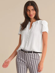 Woman wearing a white blouse and striped pants on a beige background