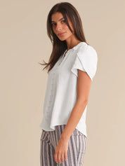 Woman wearing a light white blouse with a neutral background