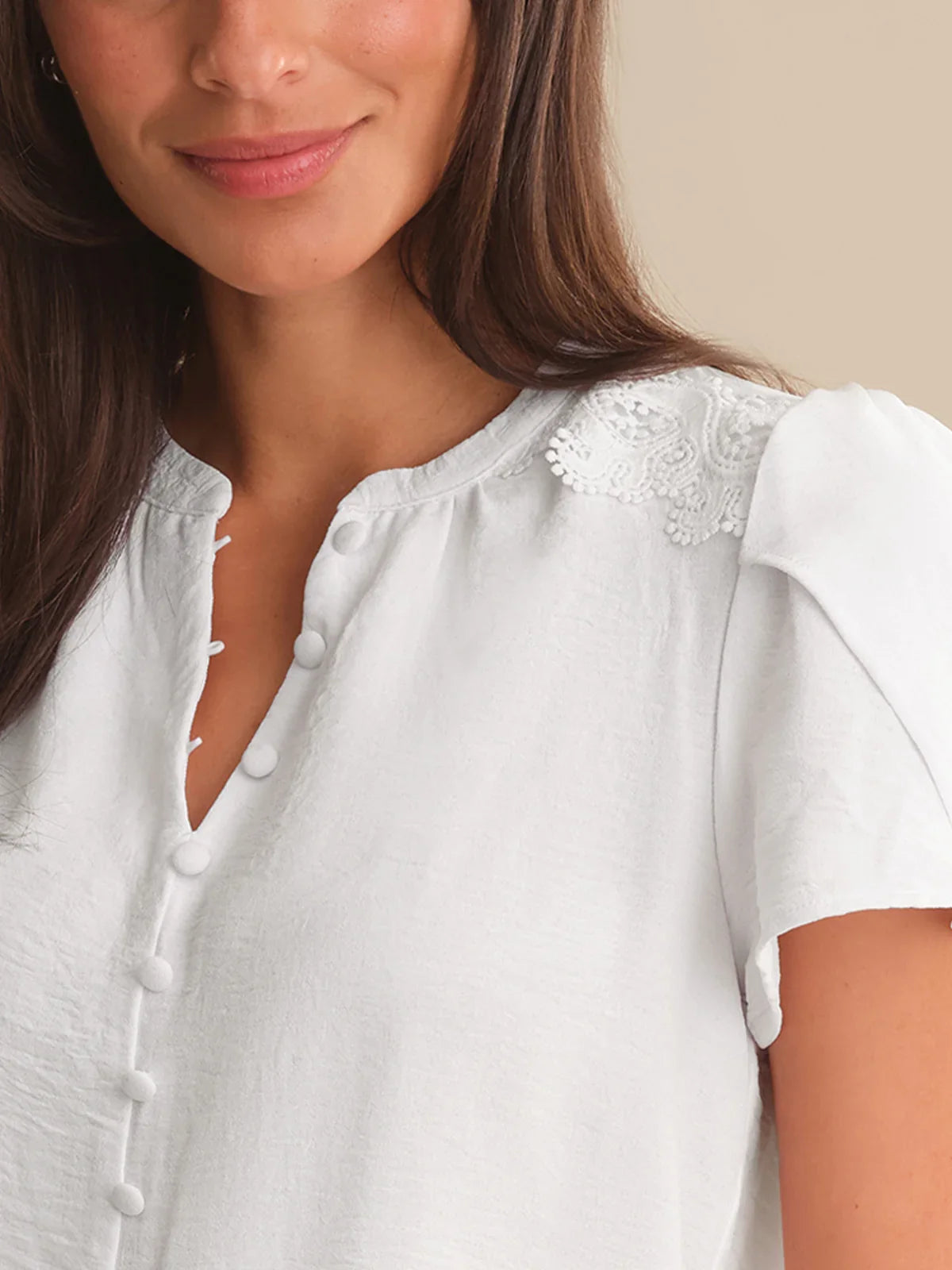 Close-up of a woman wearing a white blouse with lace details.