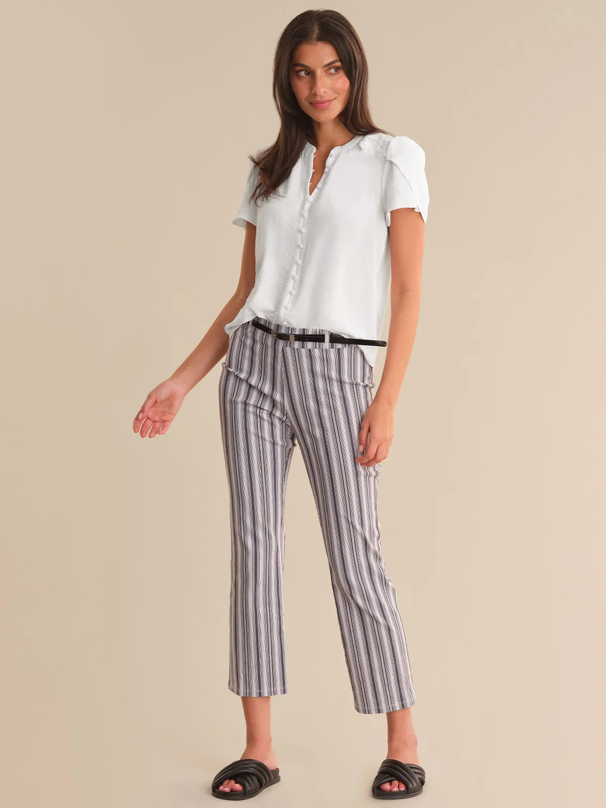 Woman wearing a white blouse and striped pants on a beige background