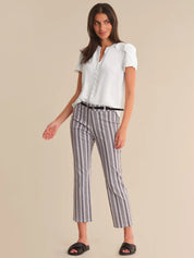Woman wearing a white blouse and striped pants on a beige background