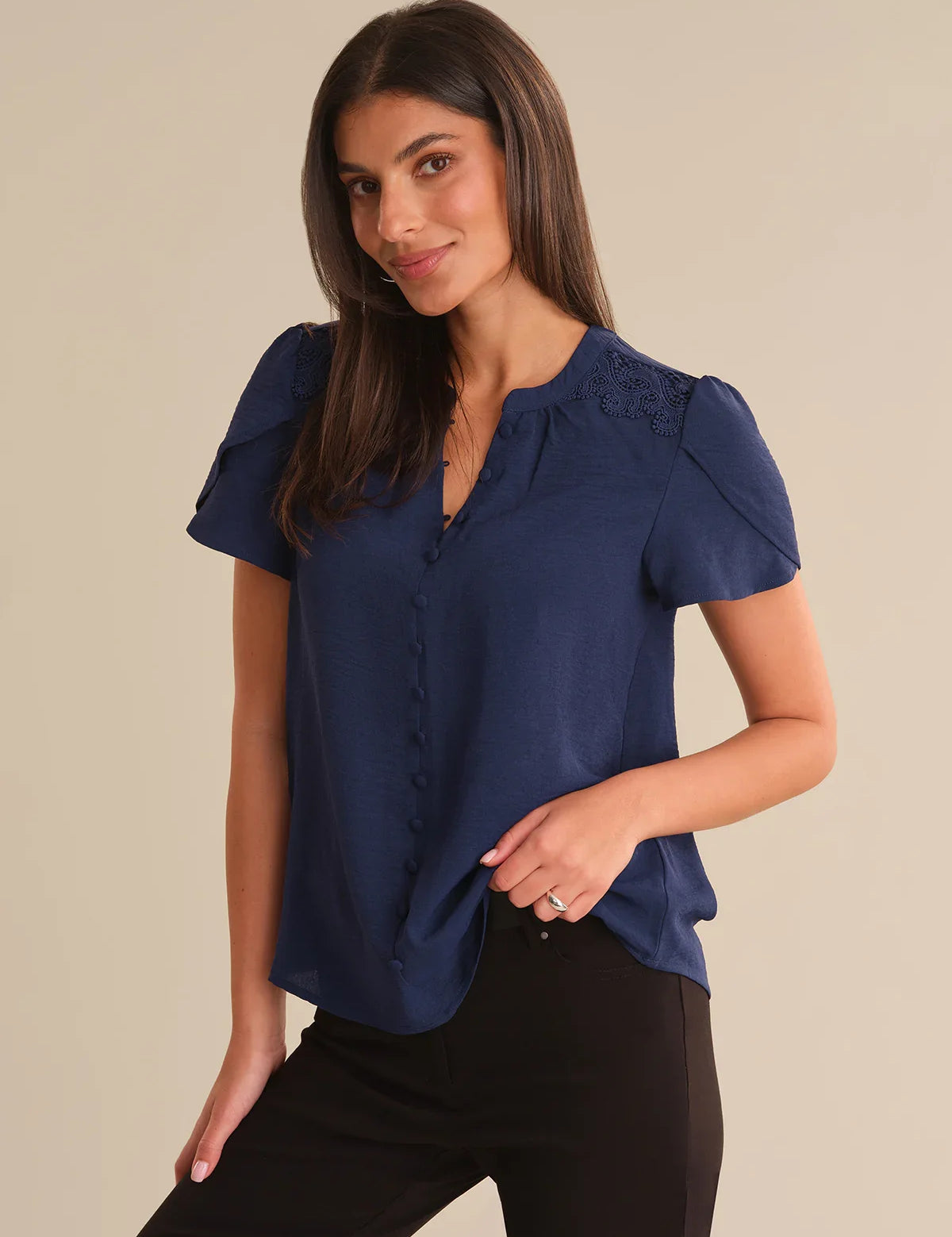 Woman wearing a blue blouse with ruffled sleeves on a beige background