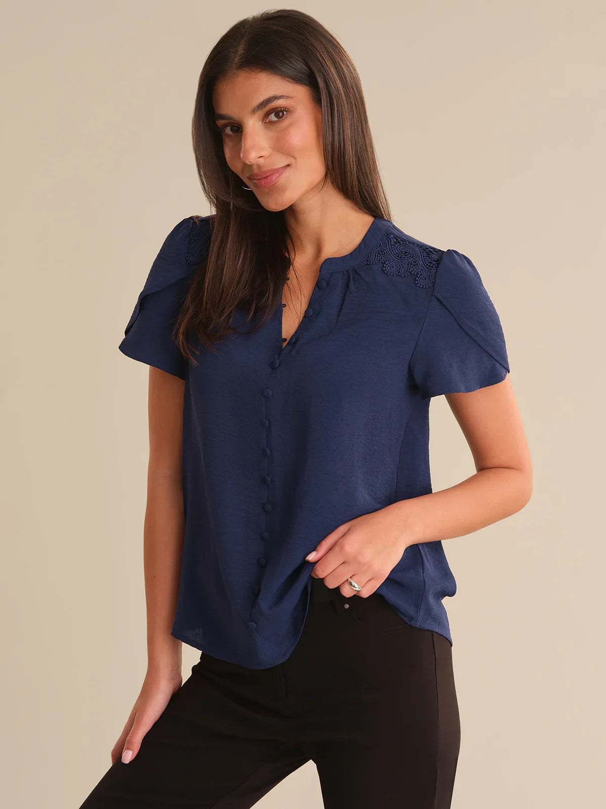 Woman wearing a blue blouse with ruffled sleeves on a beige background