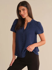 Woman wearing a blue blouse with ruffled sleeves on a beige background