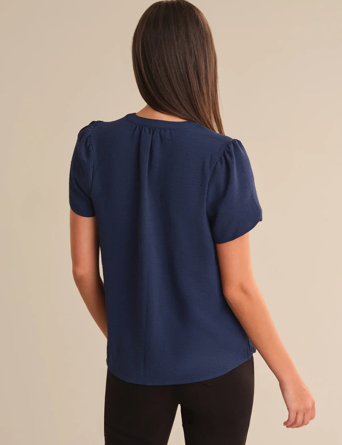 Woman wearing a navy blue blouse against a beige background