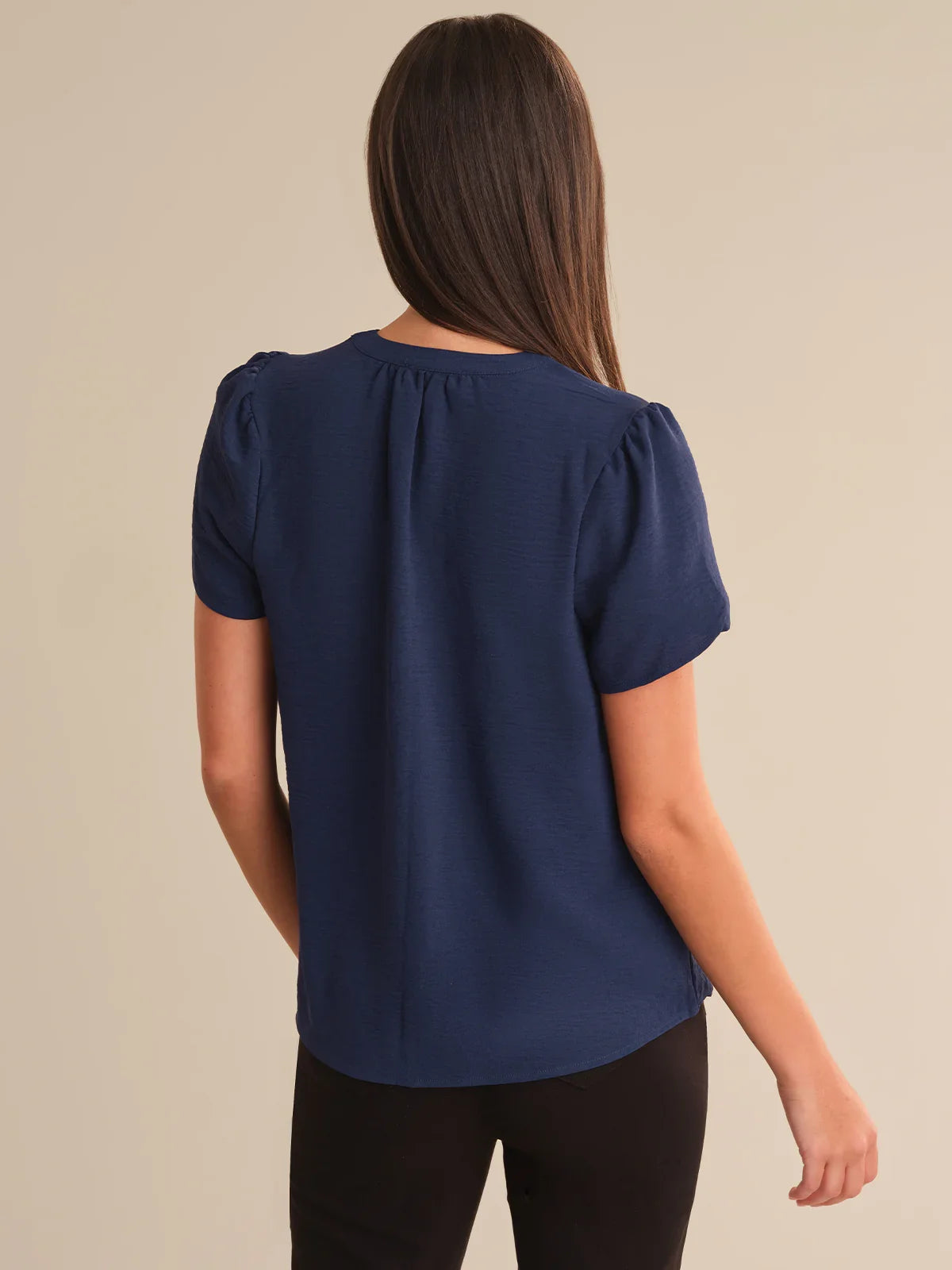 Woman wearing a navy blue blouse against a beige background