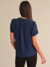 Woman wearing a navy blue blouse against a beige background