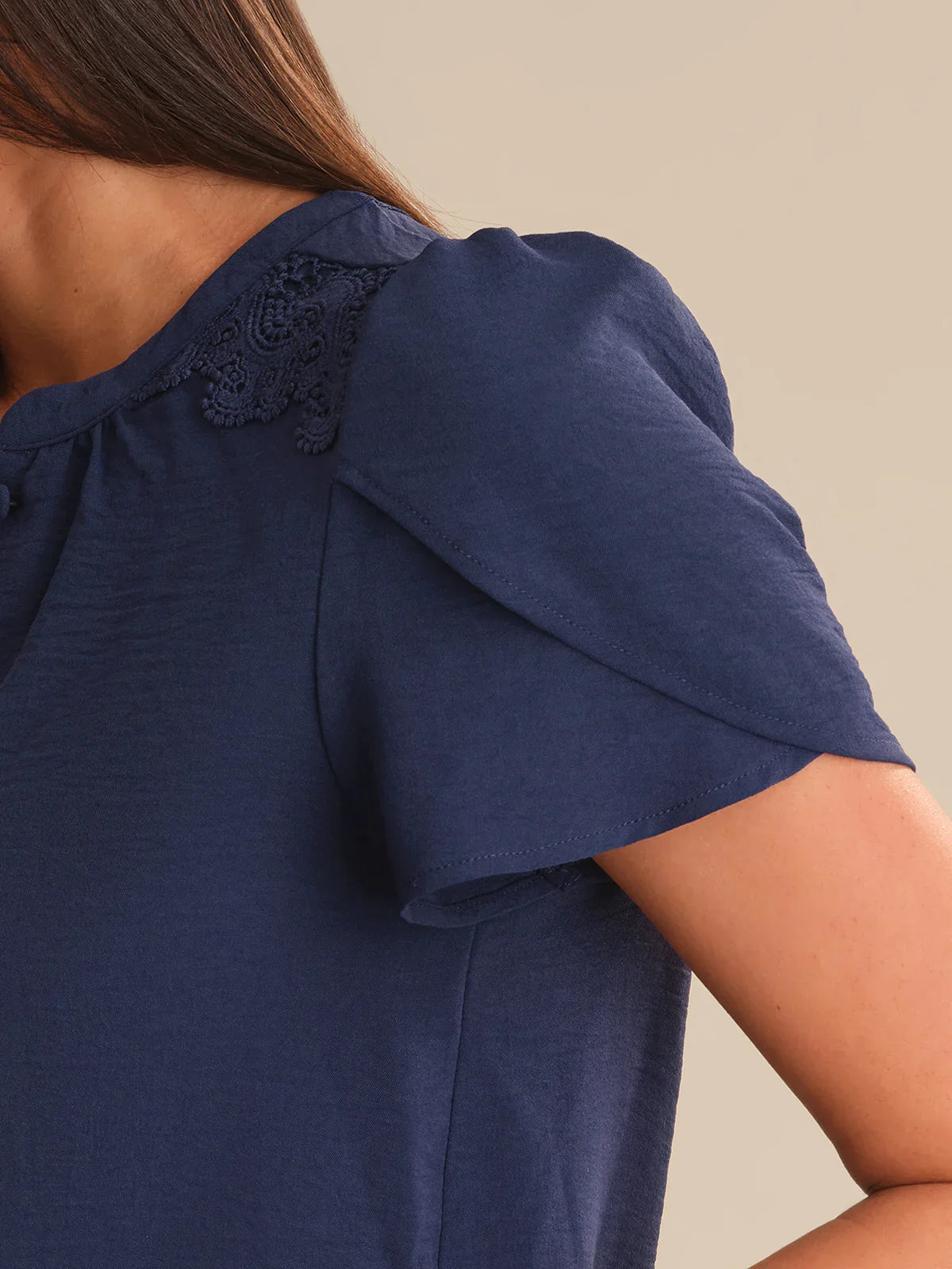Navy blue top with lace detail on a neutral background