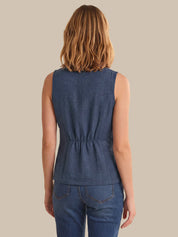 Woman wearing a blue sleeveless top and jeans on a beige background