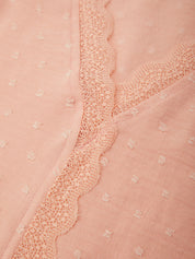 Close-up of a pink fabric with lace trim and floral patterns.
