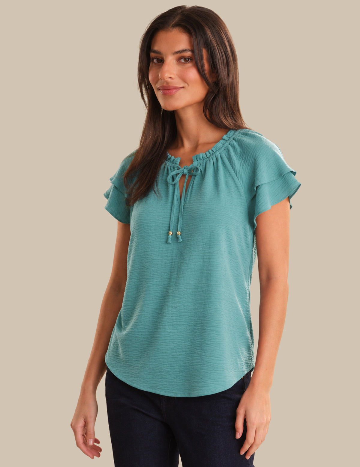 Woman wearing a teal blouse with a beige background