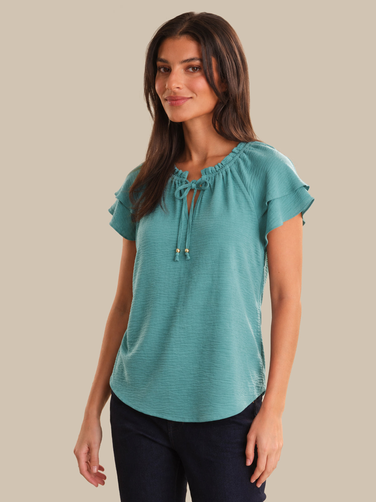 Woman wearing a teal blouse with a beige background
