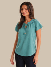 Woman wearing a teal blouse with a beige background
